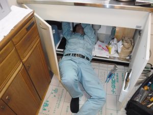 収納扉の中から水栓取り換え作業中