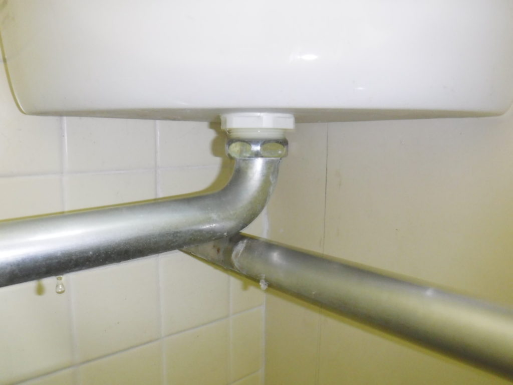 トイレタンクの水漏れ修理前の状態、タンク、洗浄管の配管から水滴が垂れています