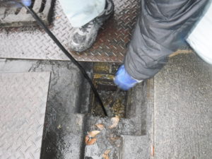 下水側溝の高圧洗浄清掃作業で詰まりの解消中